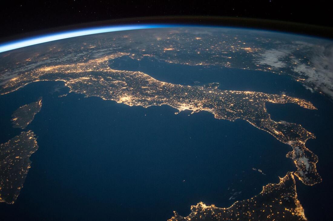 Planet earth at dusk lit up from space most visible country is Italy  