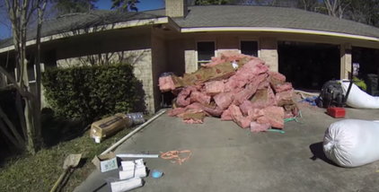 Pink fibreglass insulation piled up on the driveway in front of house 