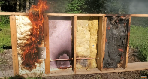 outdoors on grassy field 4 types of insulation inside a wooden panel set of fire to test for fire resistance qualities 
