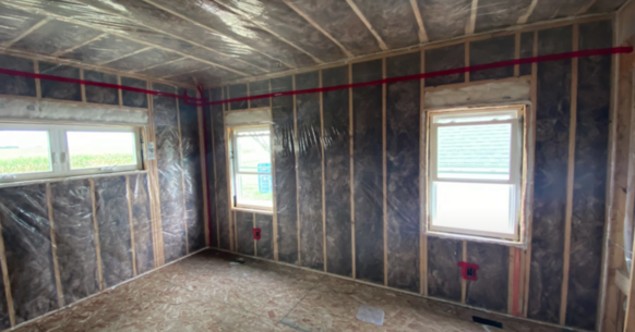 Gutted living room completely filled with batt insulation installed in the walls and ceiling 