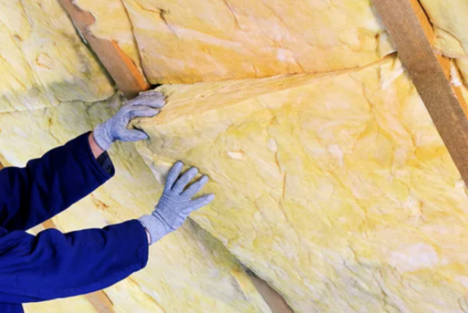 Workers gloved hands installing yellow rock-wool insulation into wall panel