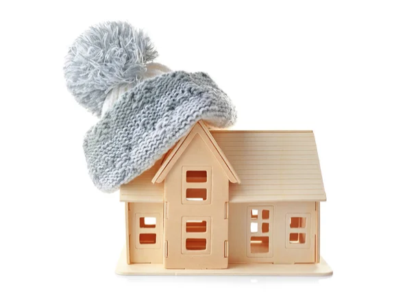  A beige model toy house wearing a blue grey tuque on the attic roof 