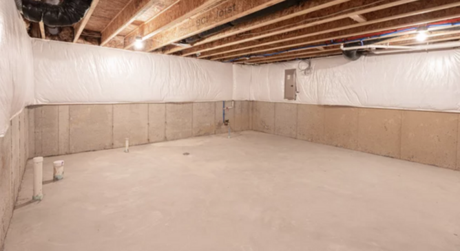 unfinished basement with grey concrete floor and wooden ceiling panels