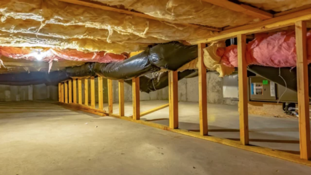 Crawl space of a house with exposed fibreglass insulation on the attic ceiling