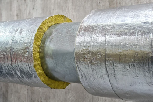 A thick pipe with insulation in front of concrete wall