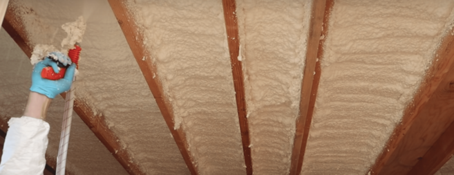 applying spray foam on ceiling in basement